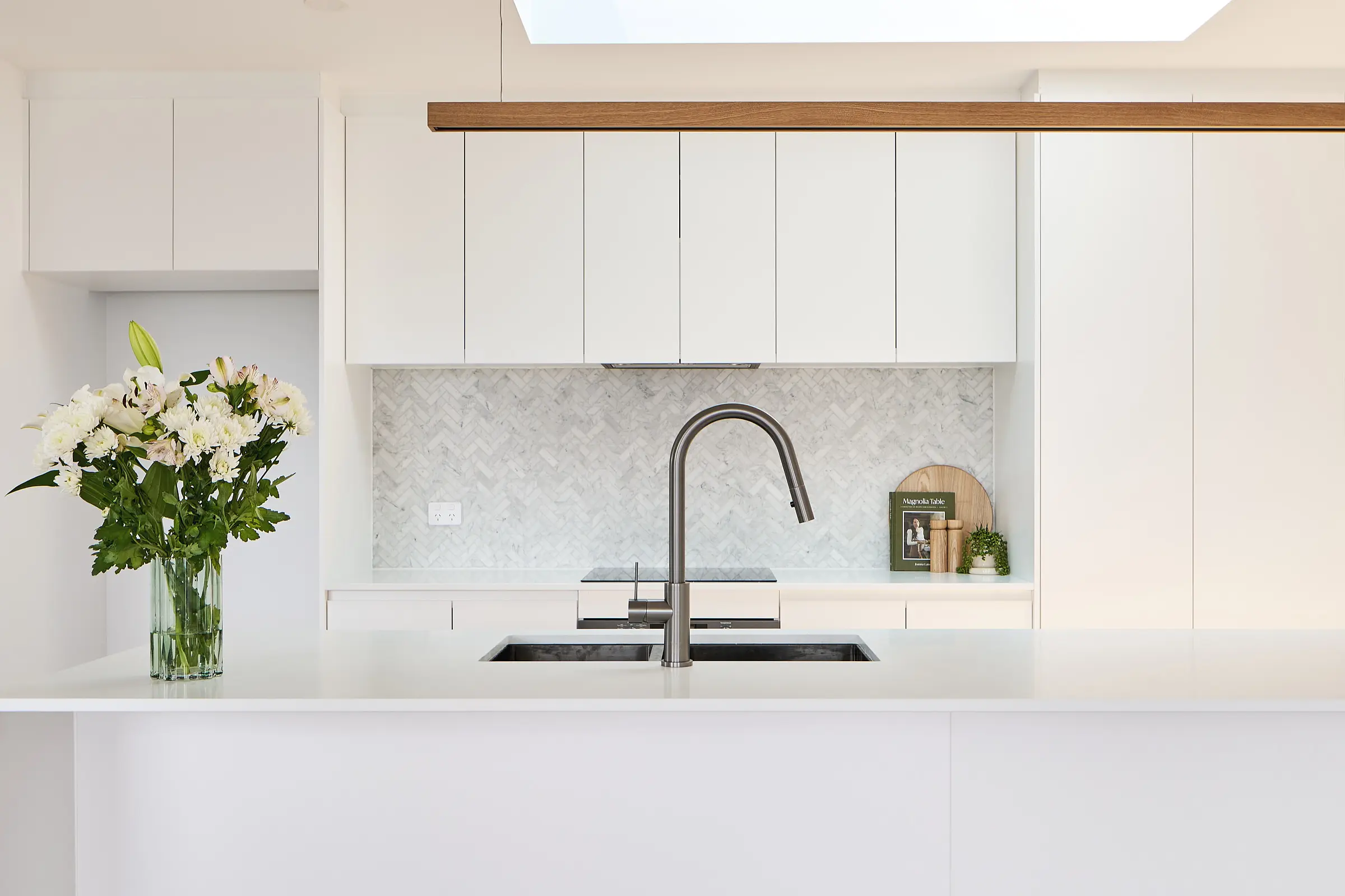 Sleek and modern kitchen design in Hobart, featuring white cabinetry and a stylish herringbone backsplash, curated by a local interior designer.